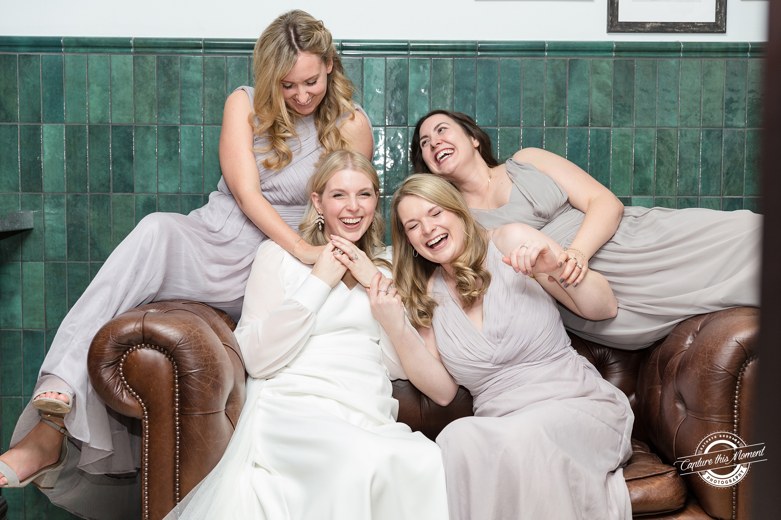 Bride and Bridesmaids giggling on sofa, Cheltenham by Kathryn Goddard Photography