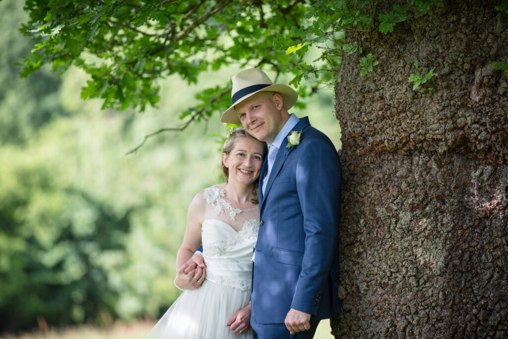 Bride and Groom find shade under a tree on their wedding day, Gloucestershire