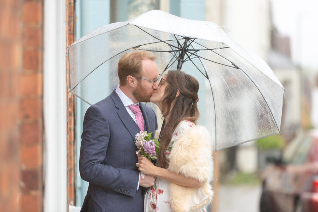 Couple under umbrella on their wedding day, Gloucestershire