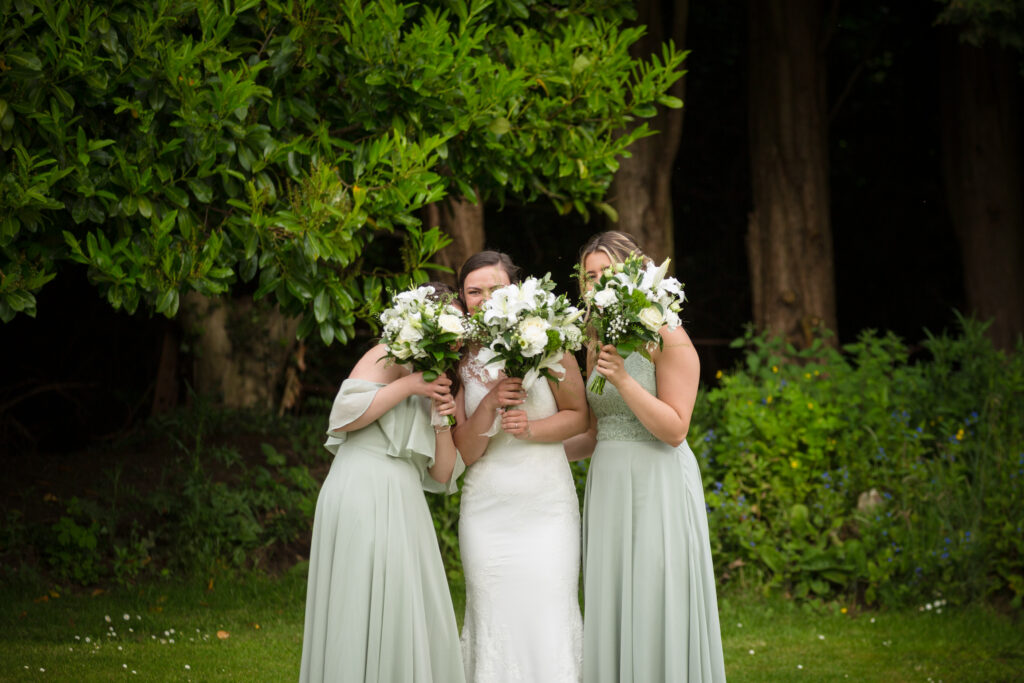 Bride and her bridesmaid giggling behind bouquets by Kathryn Goddard Photography